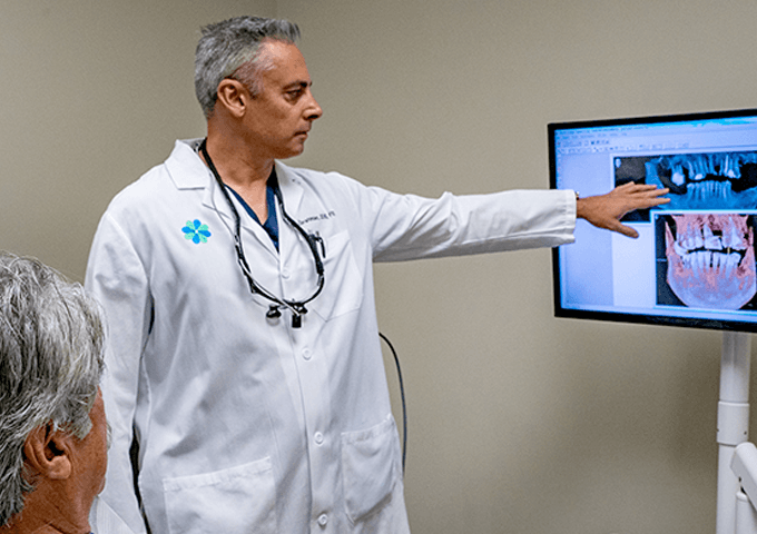 Dr. E explaining dental imaging to a seated patient.